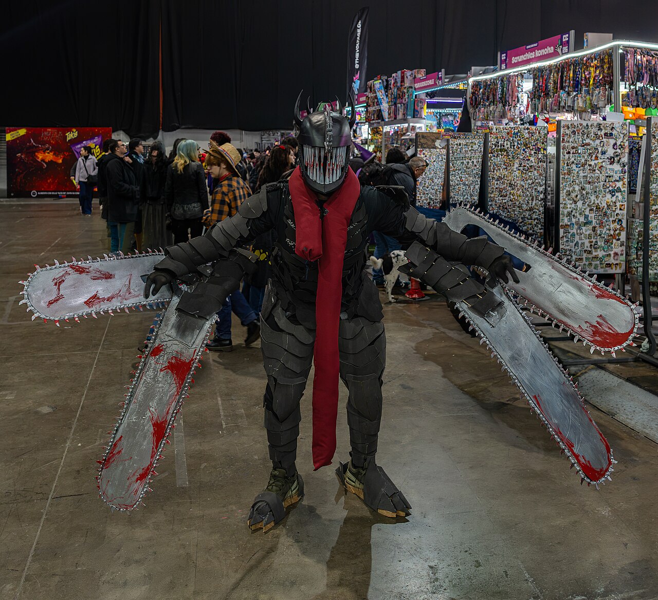 A cosplayer dressed as the Chainsaw Devil, with chainsaw blades for arms and a chainsaw-blade helmet, at a comic convention