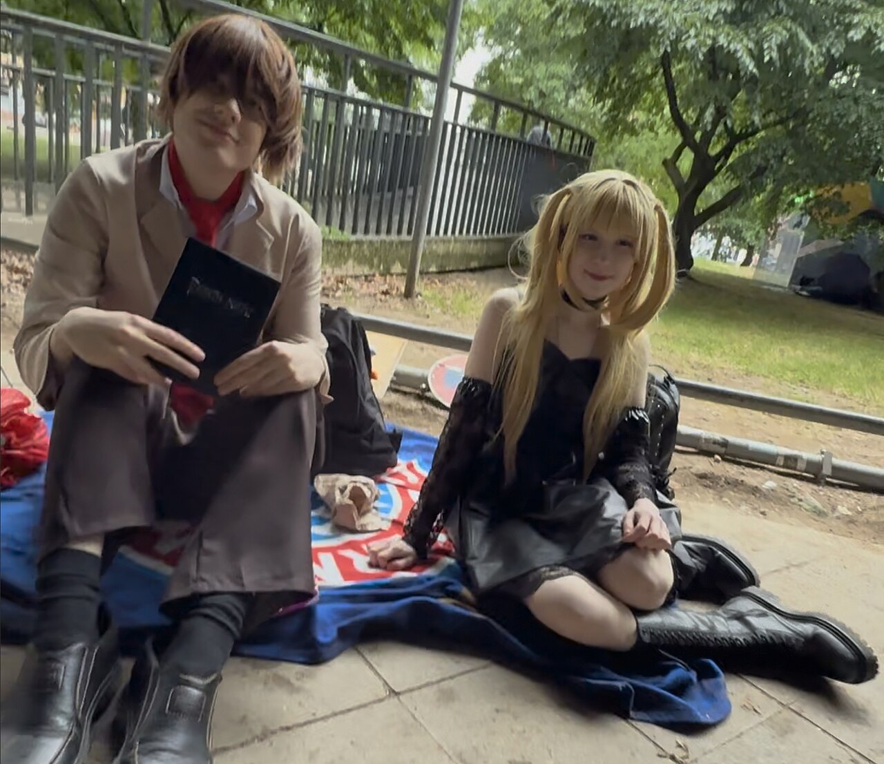 Cosplayers as Death Note's Light Yagami, holding a black notebook prop, and Misa Amane at Japantag Düsseldorf 2025