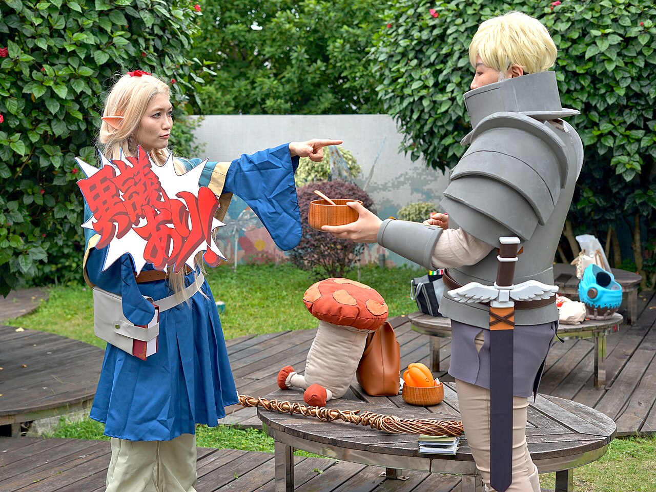Cosplayers as Marcille Donato and Laios Touden, the series' main characters, facing each other at a convention