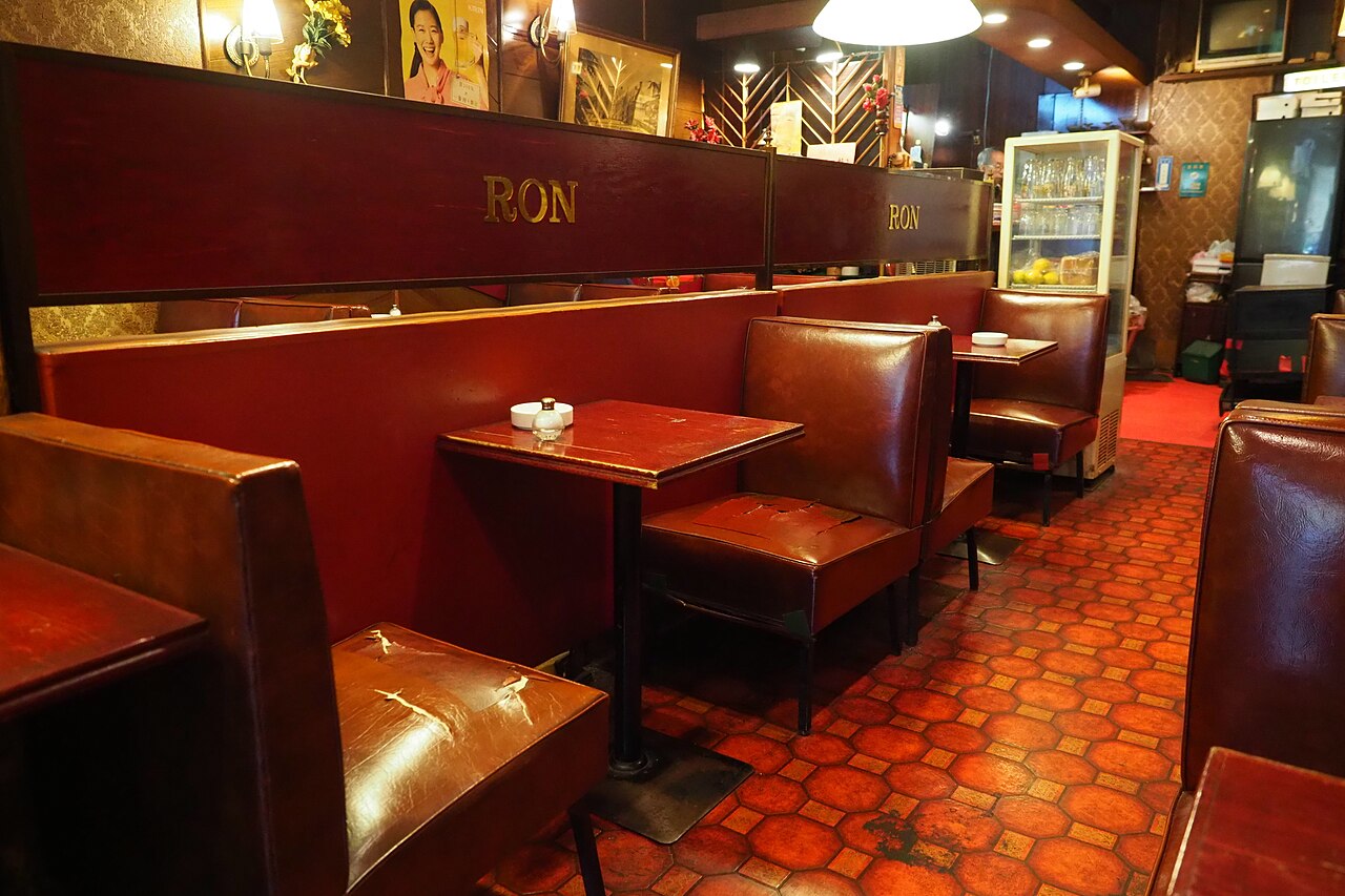 Interior of a classic kissaten with worn leather booths, wood paneling, and vintage decor