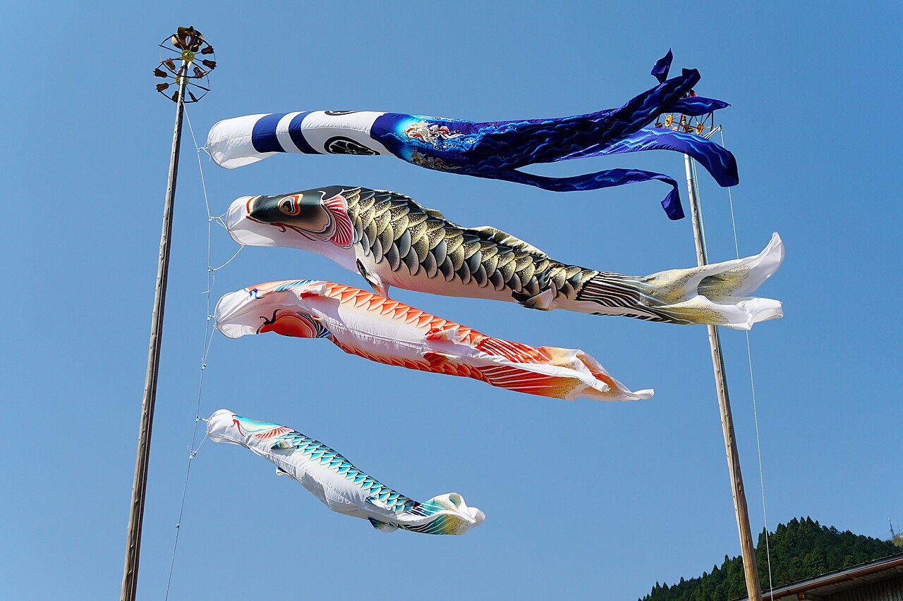 Hundreds of colorful koinobori carp streamers strung across a river valley in Chizu, Tottori prefecture, fluttering in the wind against green mountains