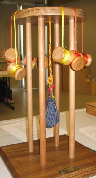 A maru-dai braiding stand with weighted tama bobbins and a cord in progress