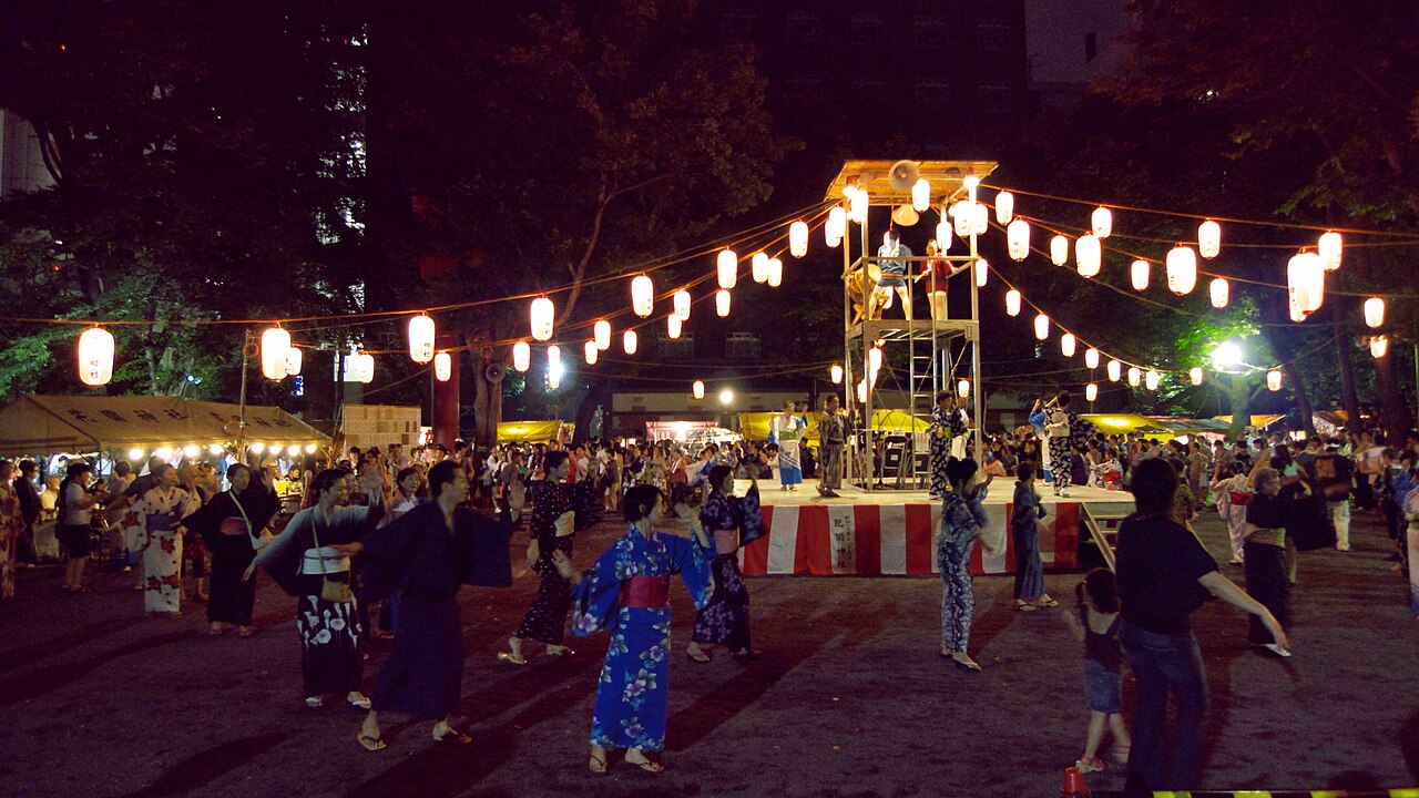 Bon odori dancers in yukata circle a yagura tower strung with chochin lanterns at Hanazono Shrine, Shinjuku, Tokyo