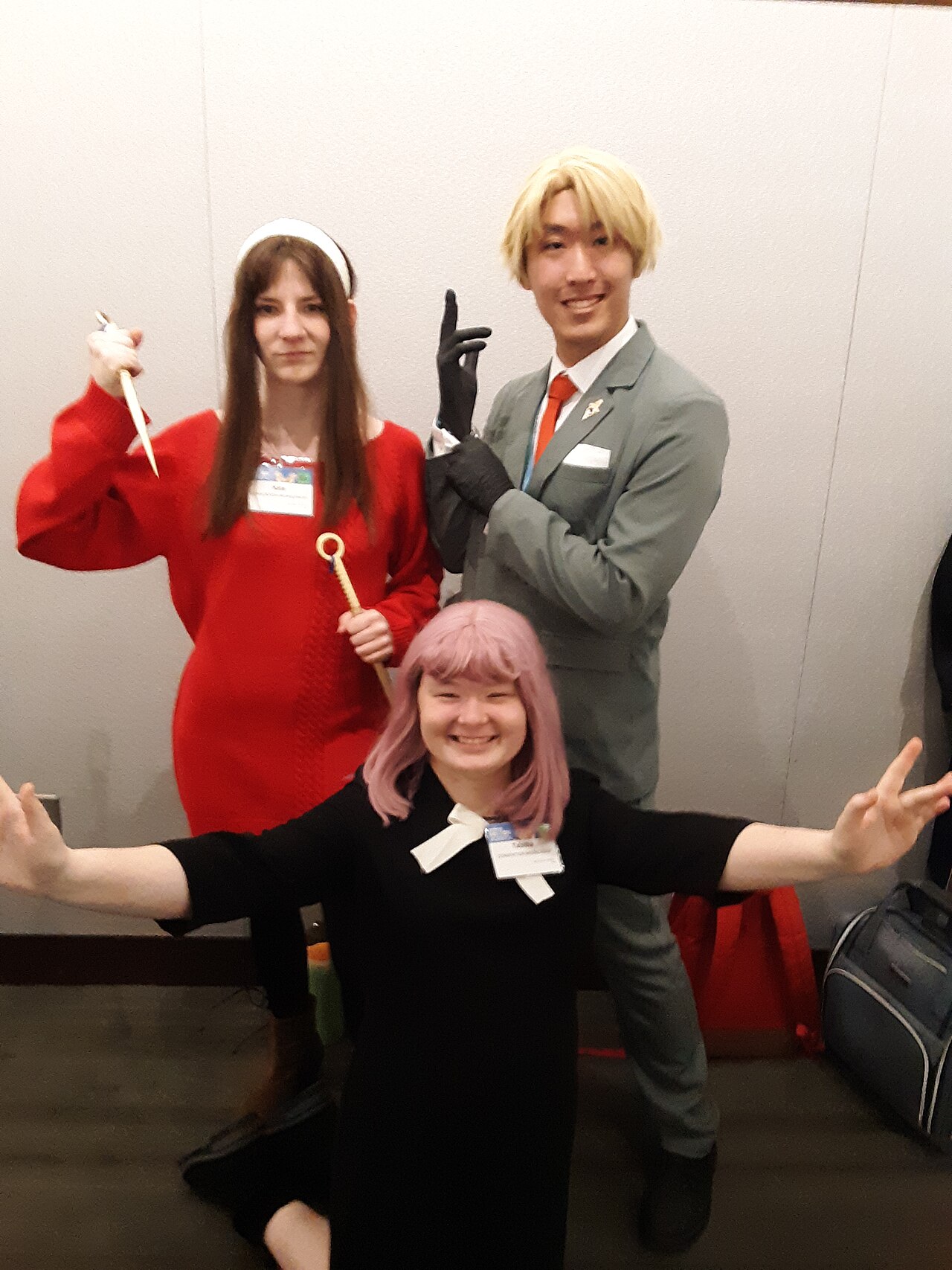 Cosplayers dressed as Anya, Loid, and Yor Forger posing together at a convention