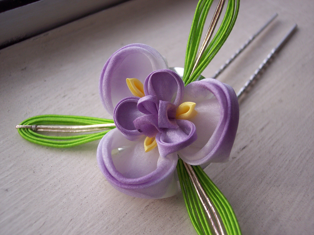 A tsumami kanzashi hair ornament made of folded silk squares, styled as an iris for the month of May
